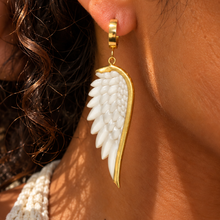 White carved angel wing earring edged in gold, worn close up - Let's Jam, Camden Market