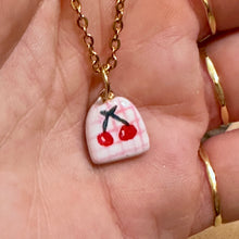 Load image into Gallery viewer, Close-up of a ceramic pendant hand painted with red cherries on pink gingham - Let's Jam, Camden Town
