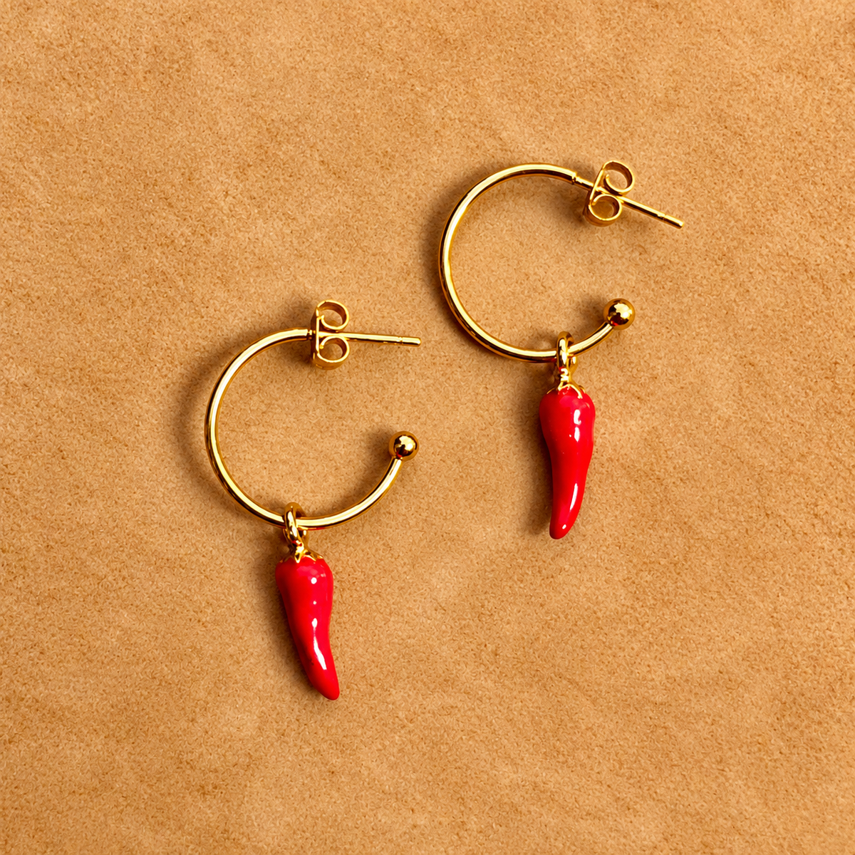 Gold hoop earrings with red chilli charms on a brown background - Let's Jam, Camden Market