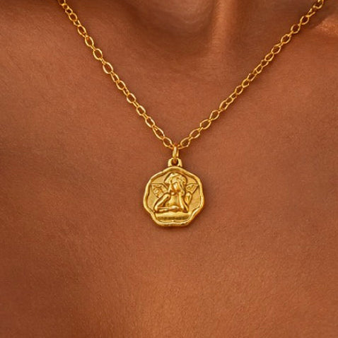 Close-up of a gold cupid medallion necklace worn - Let's Jam, Camden Town London