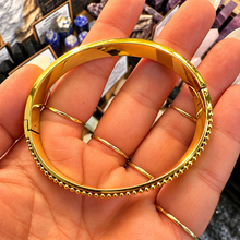 Load image into Gallery viewer, Gold arrow bangle with beaded edges laid in the palm - Let's Jam jewellery, Camden Market London
