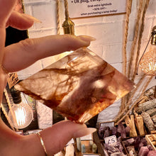Load image into Gallery viewer, Fire quartz freeform with rust-red and golden inclusions, held up to the light - Let's Jam, Camden Market
