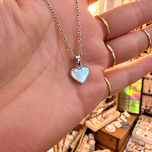 Load image into Gallery viewer, Silver framed mother of pearl heart pendant held in the hand - Let's Jam, Camden Market
