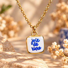 Load image into Gallery viewer, Joie de vivre hand painted ceramic pendant on a gold chain among dried flowers - Let's Jam, Camden Town
