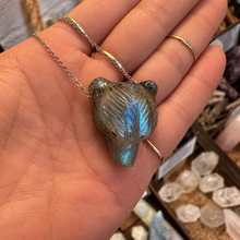 Load image into Gallery viewer, Labradorite bear pendant on a chain held in the hand in the shop - Let's Jam, Camden Town London
