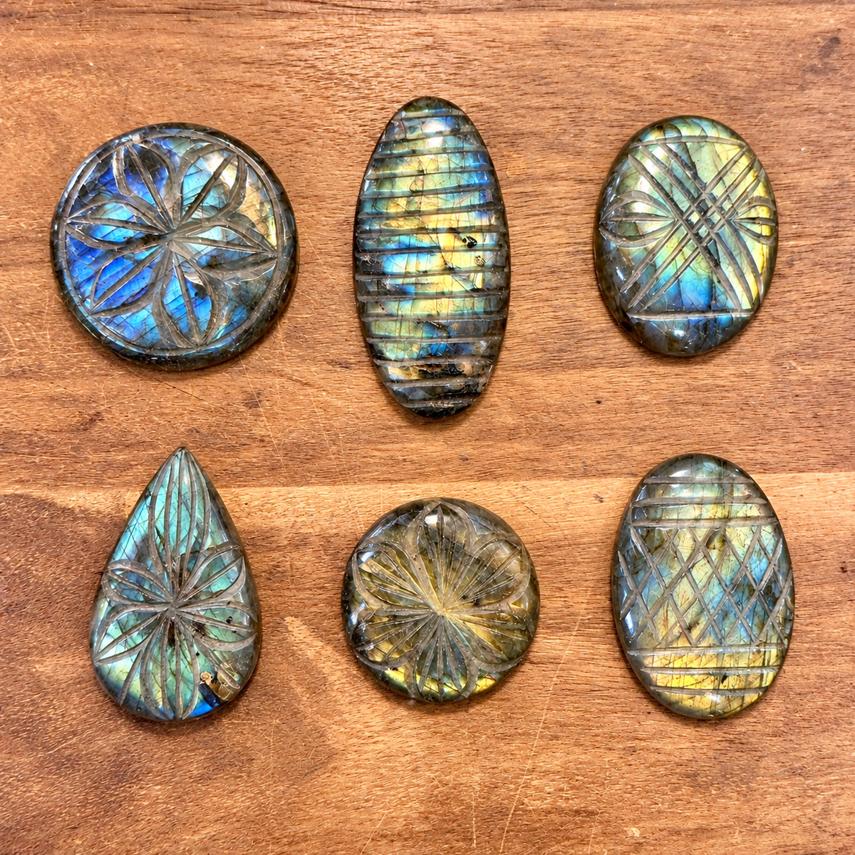 Six hand carved labradorite cabochons with flower and stripe patterns on a wooden table - Let's Jam, Camden Market