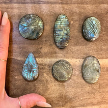 Load image into Gallery viewer, Carved labradorite cabochons next to a hand to show their size - Let's Jam, Camden Market London

