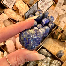 Load image into Gallery viewer, Blue lapis lazuli heart held between the fingers in the crystal shop - Let's Jam, Camden Market London
