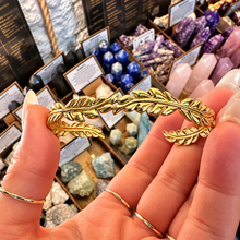 Load image into Gallery viewer, Gold cuff bangle with leaf ends held in the hand - Let's Jam, Camden Market
