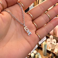 Load image into Gallery viewer, Silver LOVE word necklace held in the hand - Let's Jam, Camden Market, London
