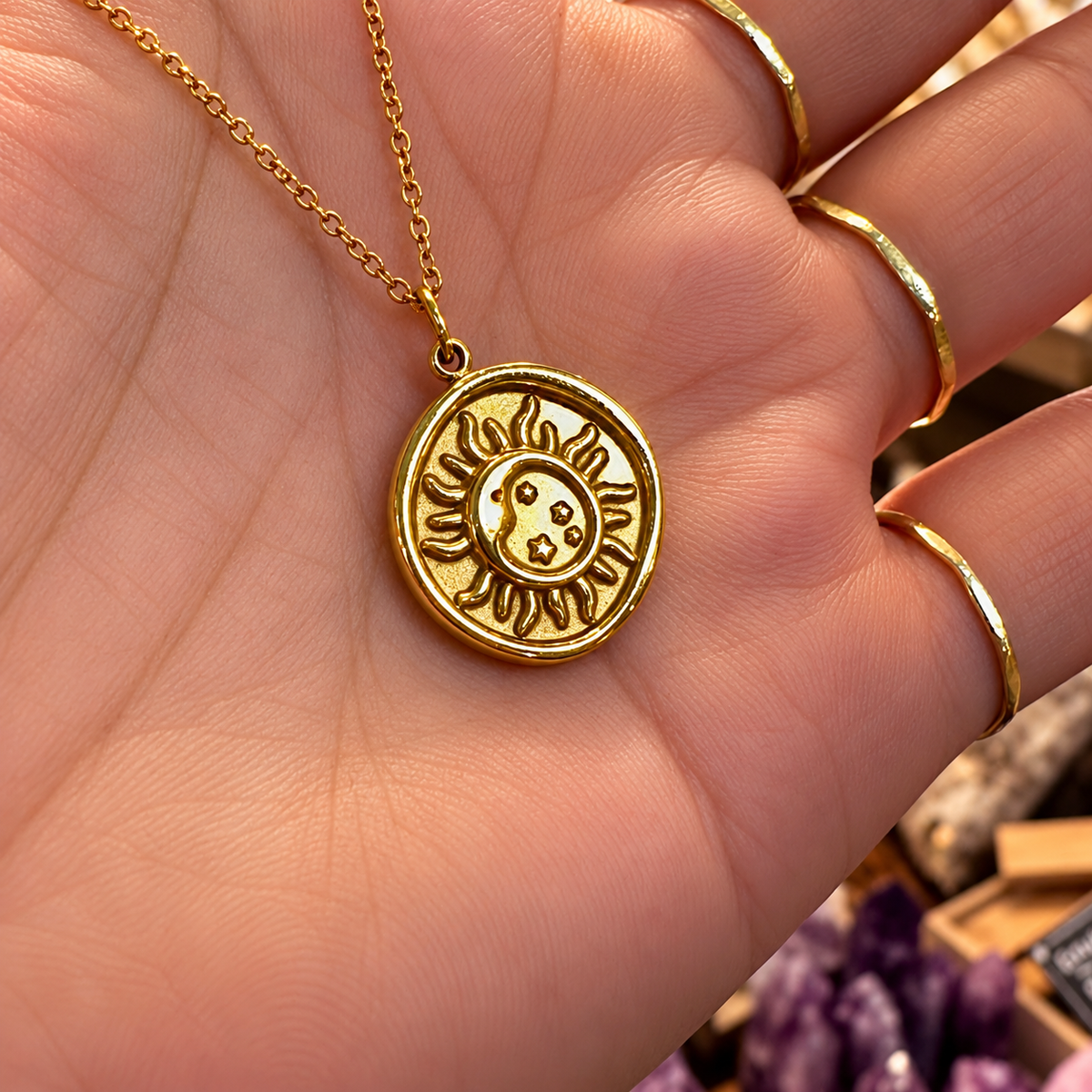 Gold moon and sun medallion held in the hand - Let's Jam jewellery, Camden Market
