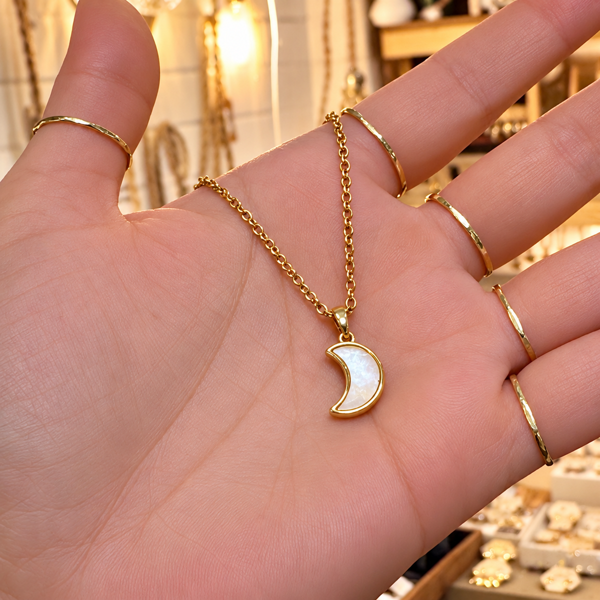Gold mother of pearl crescent moon necklace held in the hand - Let's Jam, Camden Market