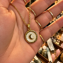 Load image into Gallery viewer, Gold round pendant with a crescent moon held in the hand - Let's Jam, Camden Market
