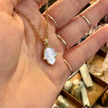 Load image into Gallery viewer, Mother of pearl hamsa hand pendant on a gold chain held in the hand - Let's Jam, Camden Town London

