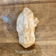 Load image into Gallery viewer, Raw milky quartz point number two on a wooden table - Let's Jam, Camden Market, London
