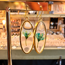 Load image into Gallery viewer, Oval resin earrings with a single real green flower on a gold stand in the shop - Let's Jam jewellery, Camden Market
