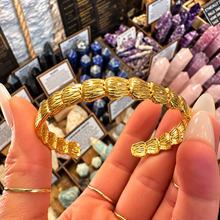 Load image into Gallery viewer, Front of the gold shell cuff bangle held up - Let's Jam, Camden Town
