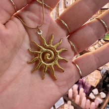 Load image into Gallery viewer, Gold spiral sun pendant held in the hand - Let's Jam, Camden Market London
