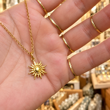 Load image into Gallery viewer, Gold sun pendant held in the hand - Let's Jam, Camden Market, London

