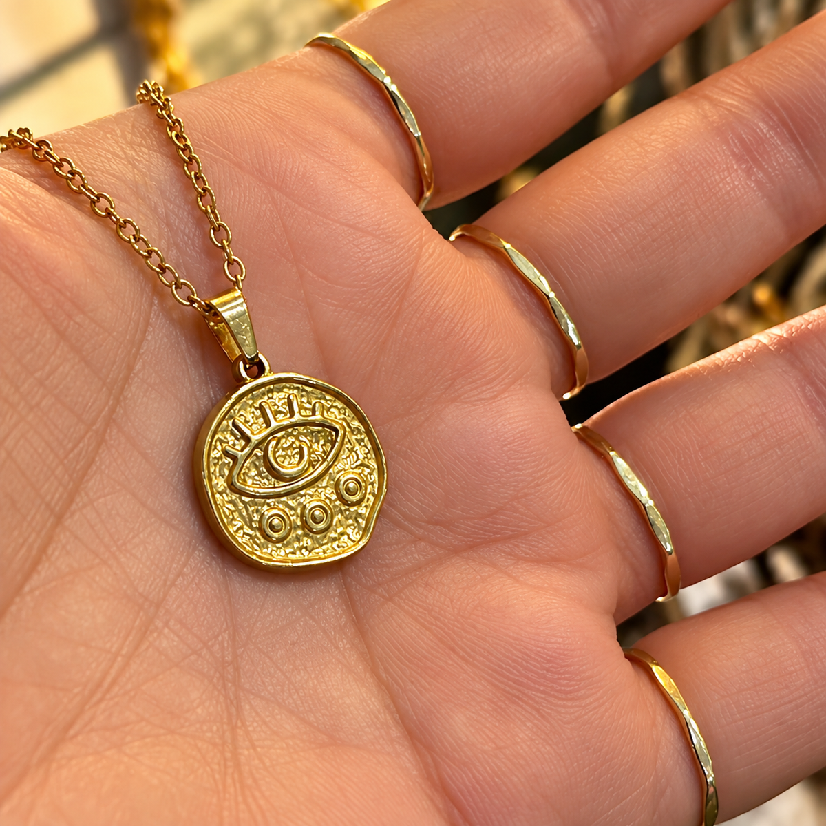 Gold third eye medallion held in the hand - Let's Jam, Camden Market London