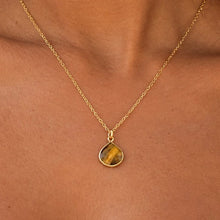 Load image into Gallery viewer, Close-up of a tiger's eye pendant on a fine gold chain, worn - Let's Jam jewellery, Camden Market London
