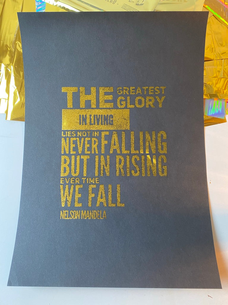 A gold holographic print of a Nelson Mandela quote about rising every time we fall, printed in bold gold type on a dark background - Let's Jam print collection