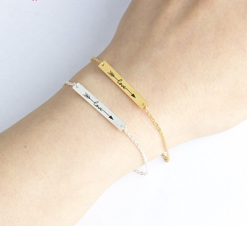 Gold and silver bar bracelets engraved with 'love' and arrow design on wrist - Let's Jam jewellery collection
