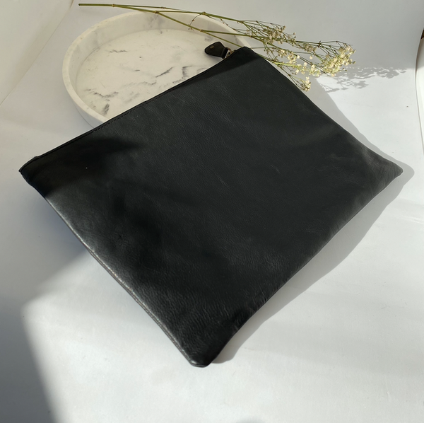 Handmade black leather clutch bag with a zip pocket, styled on a marble dish with dried flowers - Let's Jam collection