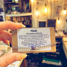 Load image into Gallery viewer, Handmade stainless steel bracelet with a real black pearl charm, held alongside a printed card describing the stone's healing properties - Let's Jam jewellery collection
