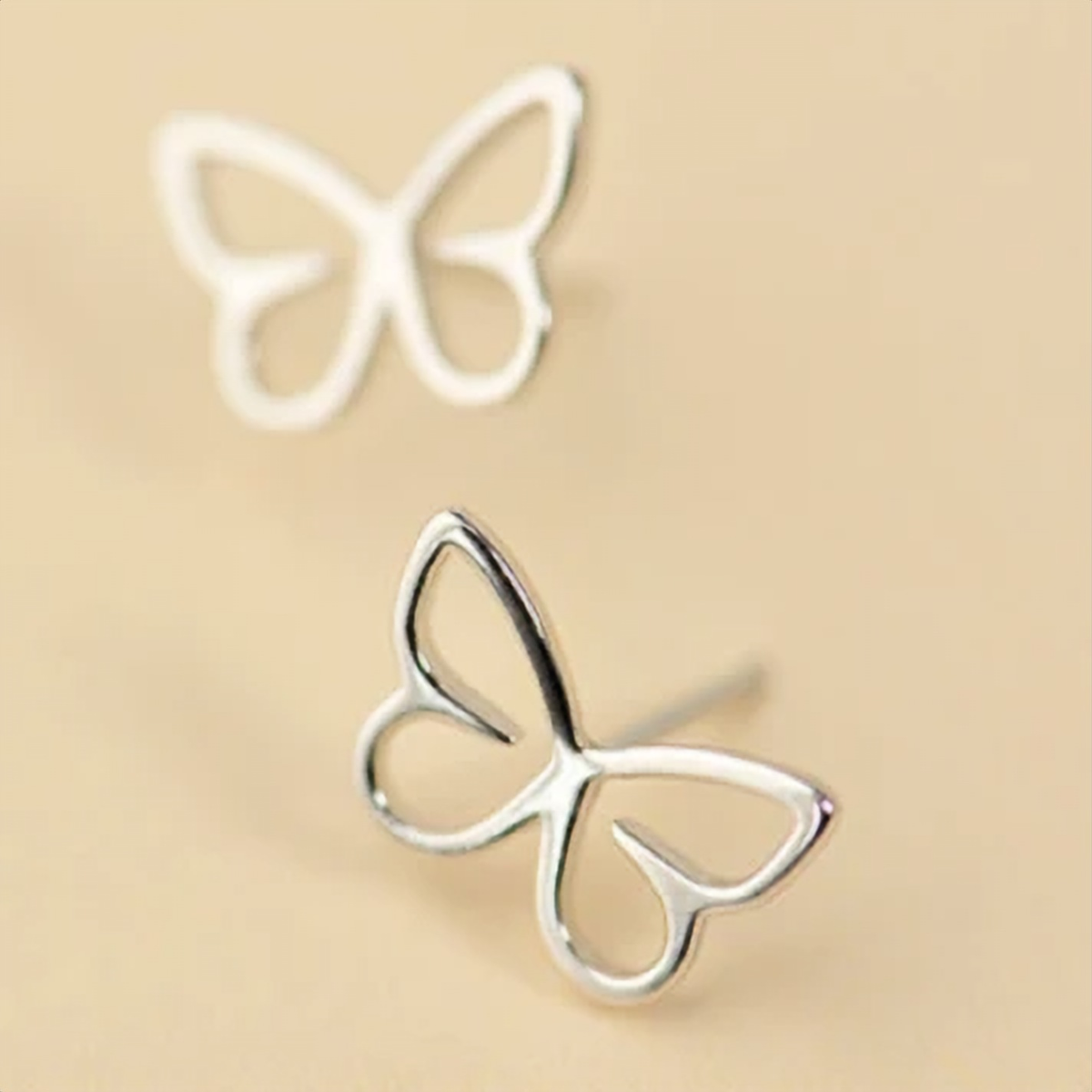 925 sterling silver hollow wire outline butterfly stud earrings on a beige background - Let's Jam jewellery collection